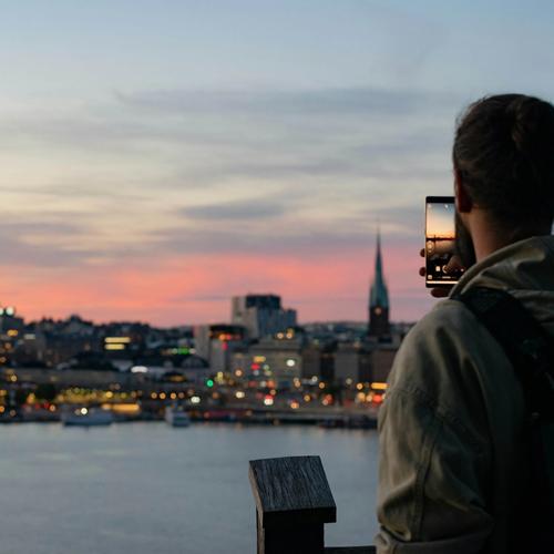 Mies ottaa valokuvaa Tukholman siluetin auringonlaskusta. Valokuva.