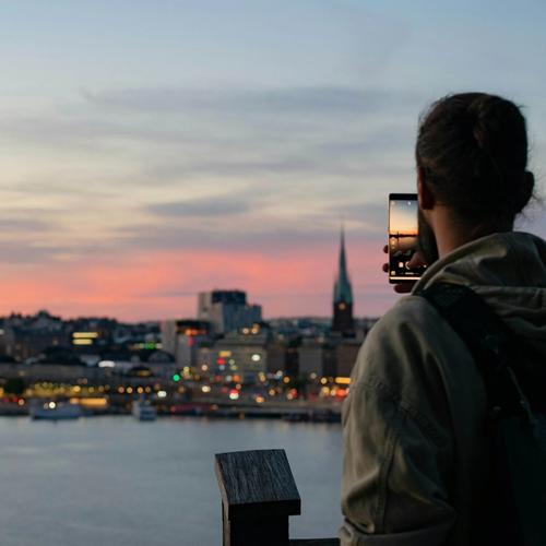 Mies ottaa valokuvaa Tukholman siluetin auringonlaskusta. Valokuva.