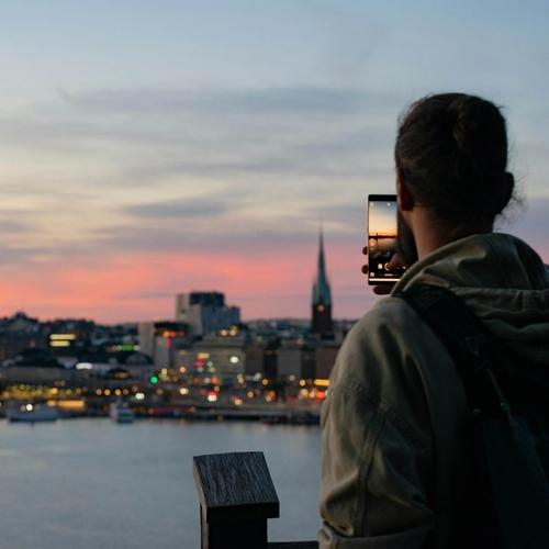 Mies ottaa valokuvaa Tukholman siluetin auringonlaskusta. Valokuva.