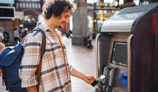 En man står på centralstationen och köper tågbiljett. Han betalar enkelt med Google pay i mobilen. foto.