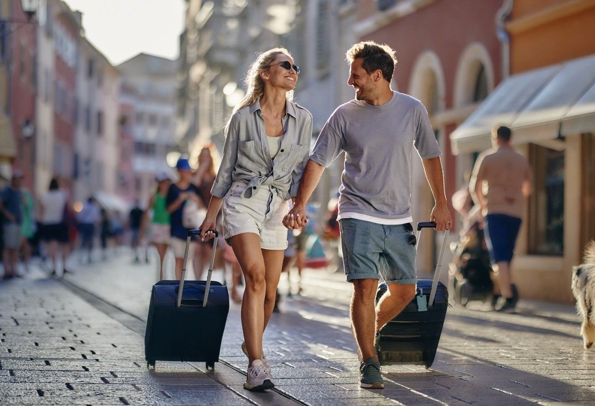 Man og kvinne er på reise. De holder hånd og drar hver deres trillekoffert. bilde.