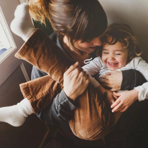 Mor som holder barnet sitt i fanget. barnet ler. bilde.