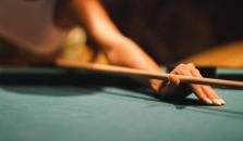 En kvinne med hvit neglelakk spiller biljard