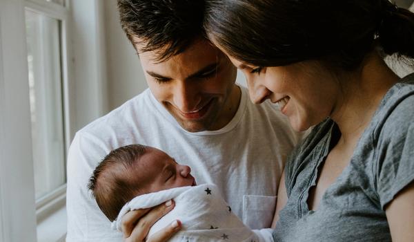Föräldrar med sitt nyfödda barn. De ser glada ut.