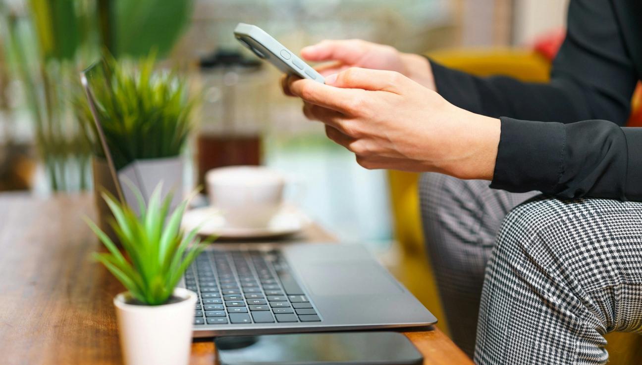 Man bruker BankID på mobil sin når han sitter ved pc. bilde.