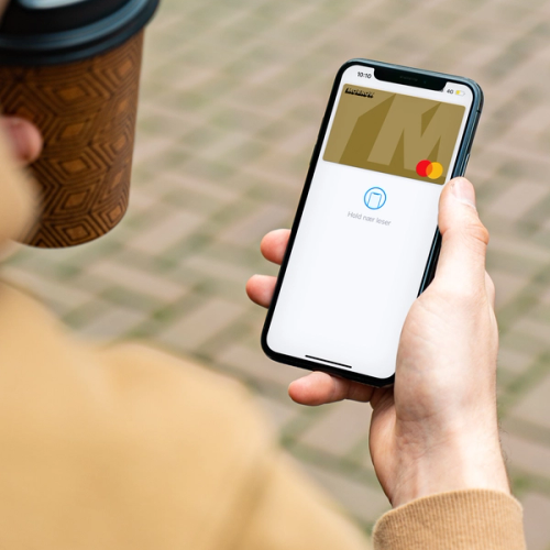 Mann har kaffe i den ene hånden og mobil med Morrow digitalt gullkort i den andre. bilde.