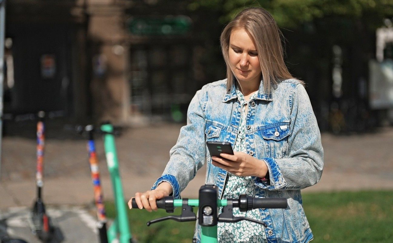 Kvinna betalar elsparkcykel med digitalt plånbok i sin mobil. foto.