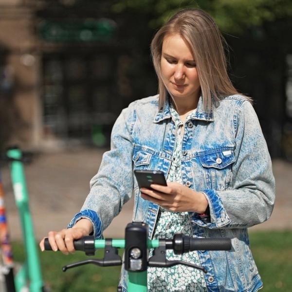 Kvinna betalar elsparkcykel med digitalt plånbok i sin mobil. foto.