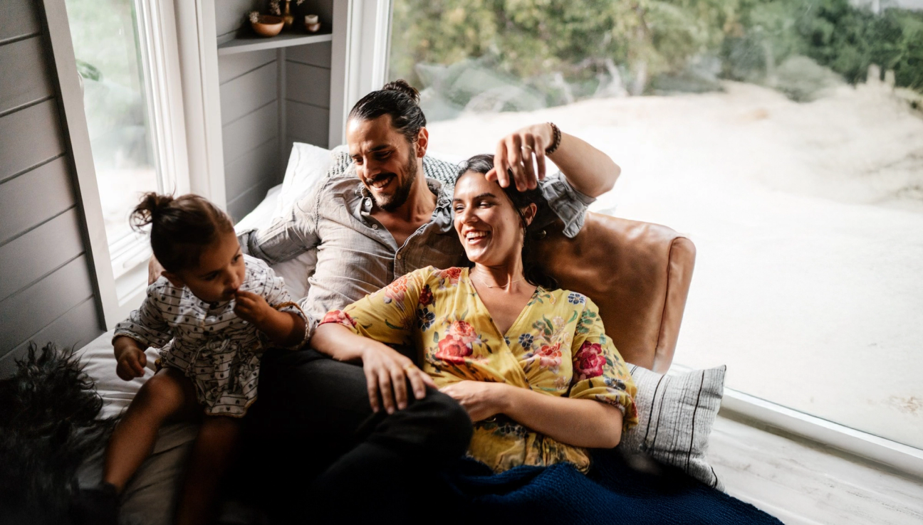 En familie på tre koser seg på sofaen. bilde.