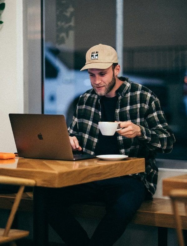 Mies hakee lainaa tietokoneella kahvilassa. Valokuva.