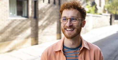 A man with red hair and glasses smiling big. picture.