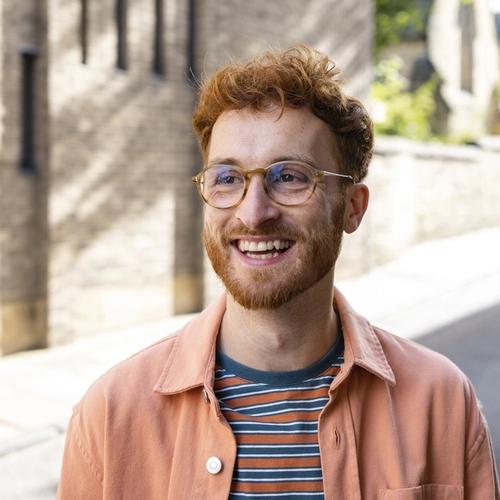 A man with red hair and glasses smiling big. picture.