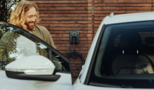 Mies hymyilee ja katsoo uutta autoaan. Valokuva.