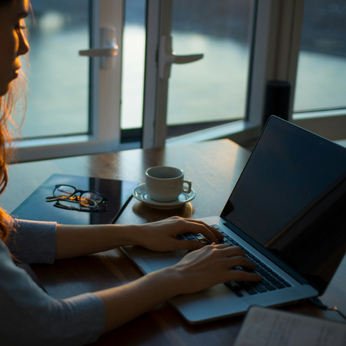 Kvinna sitter vid ett bord och använder en laptop för att ansöka om lån hos Morrow Bank