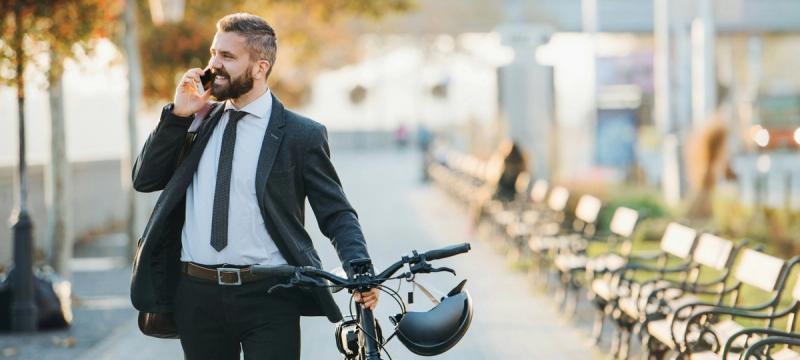 A nicely dressed man with a bike. It is Autumn.