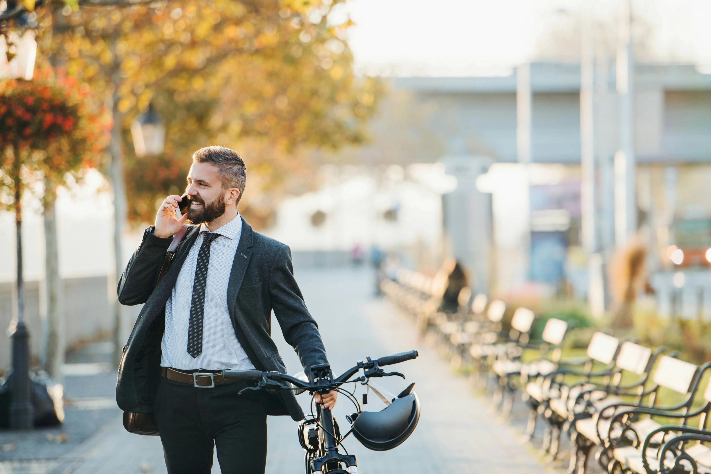 A nicely dressed man with a bike. It is Autumn.