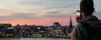 En man tar bild på Stockholms siluett i skymning