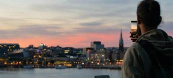 En man tar bild på Stockholms siluett i skymning