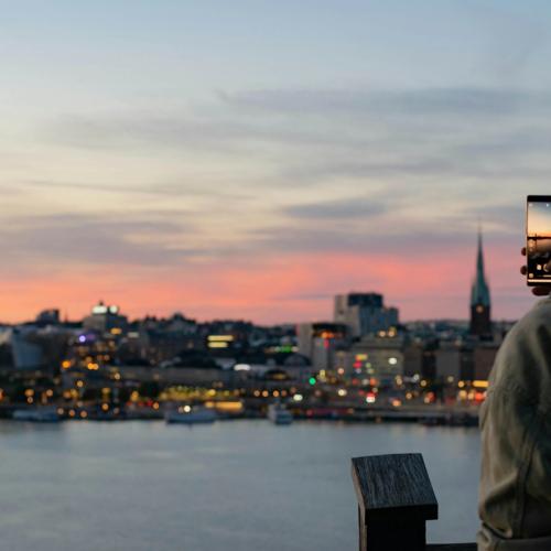 En man tar bild på Stockholms siluett i skymning
