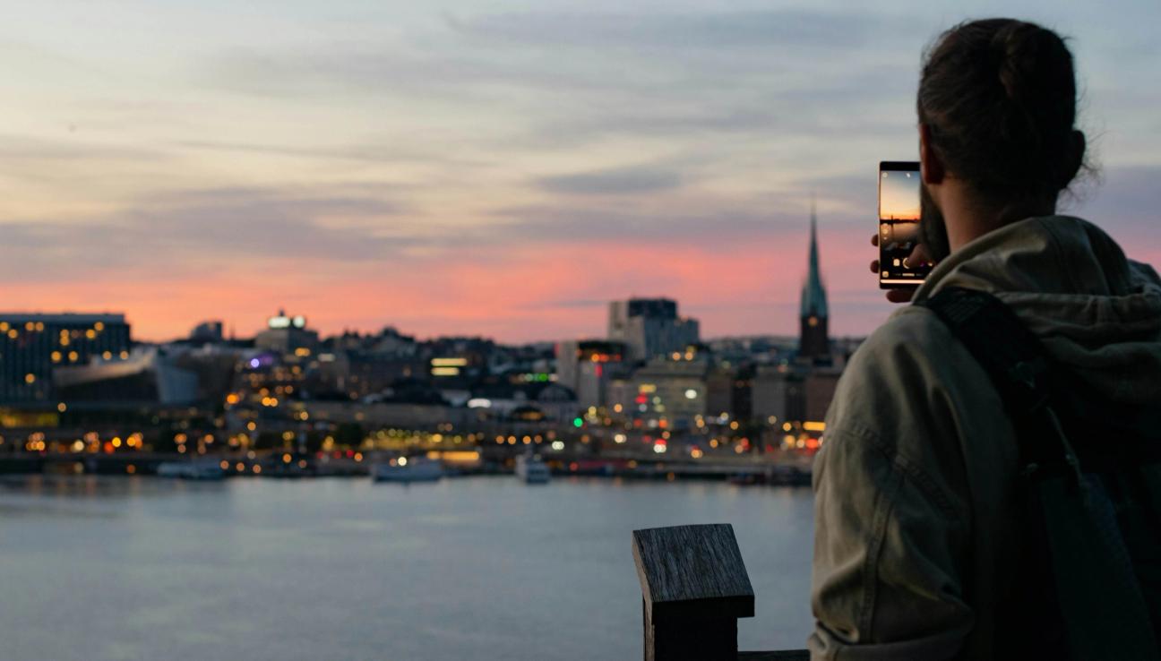 En man tar bild på Stockholms siluett i skymning
