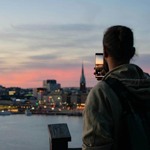 En man tar bild på Stockholms siluett i skymning