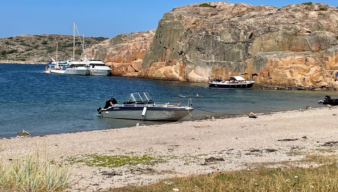 Småbåtar i en vik med sandstrand och klippor på svenska västkusten.