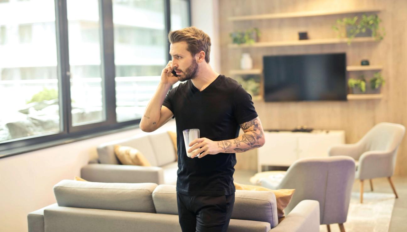 Man går runt i vardagsrummet och pratar i telefon