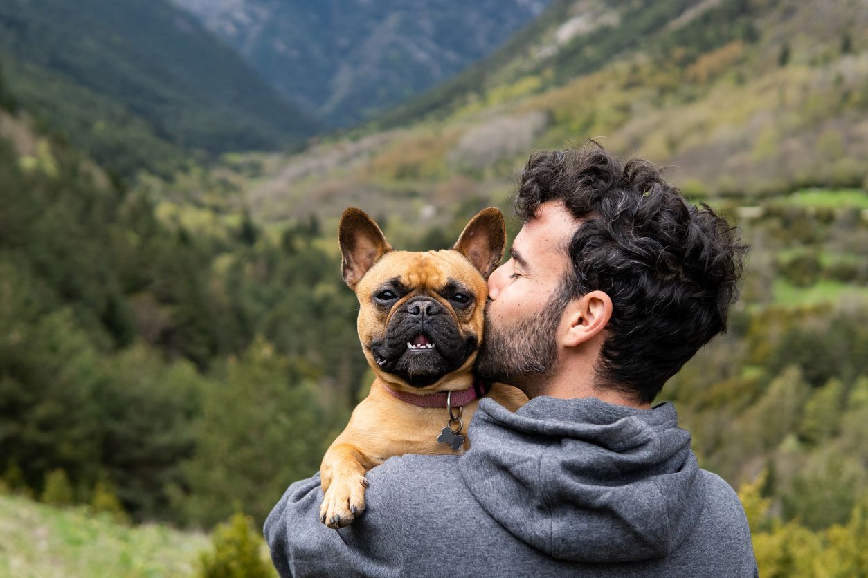 En mann holder hunden sin og kysser den på hodet. bilde.