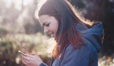 En jente ser ned i mobilen sin. bilde.