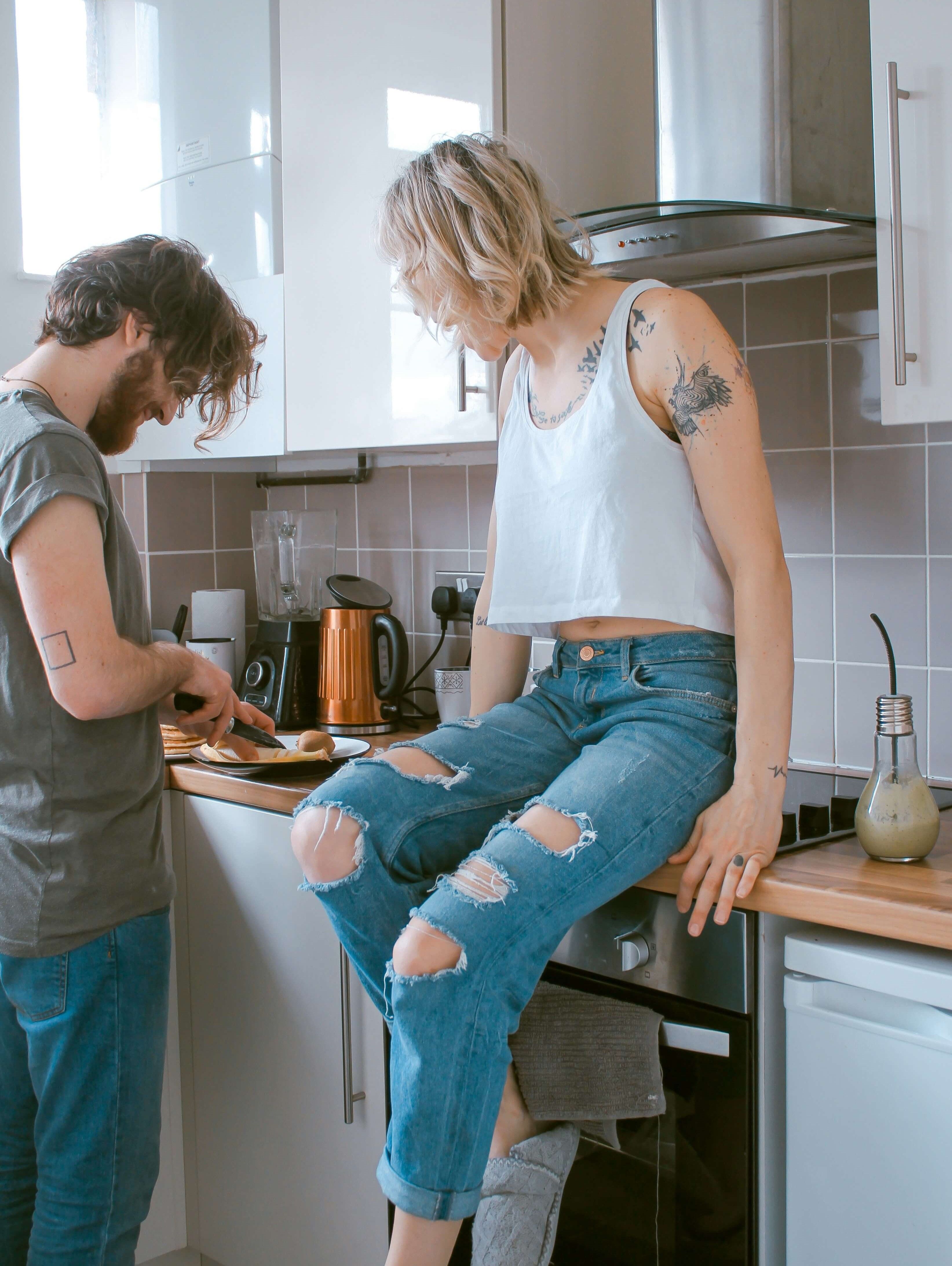 A young couple in the kitchen. The woman is sitting on the bench. picture.