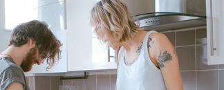 A young couple in the kitchen. The woman is sitting on the bench. picture.