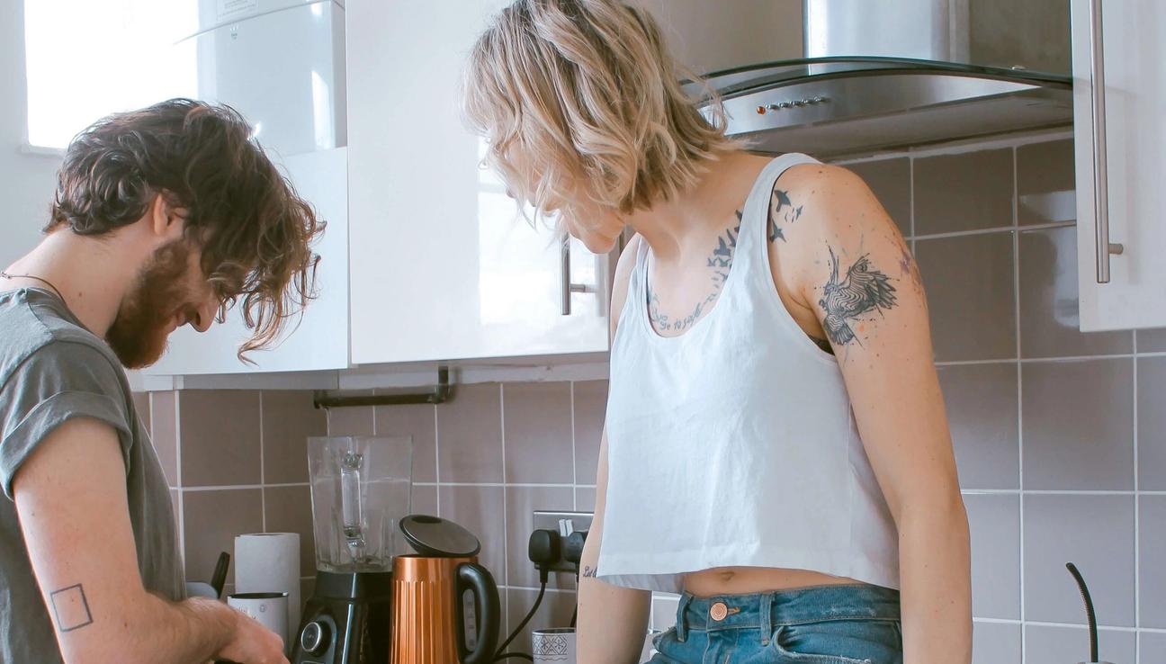 A young couple in the kitchen. The woman is sitting on the bench. picture.