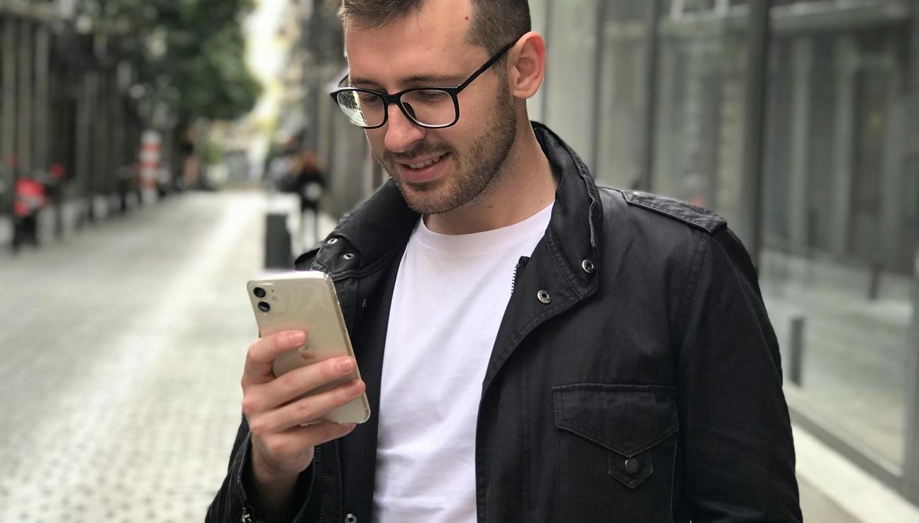 Mies pitelee matkapuhelintaan MobilePay-maksun suorittamiseksi. kuva.