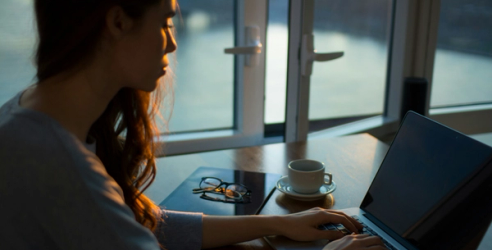 Dame sitter ved sin pc og søker om lån fra Morrow Bank.