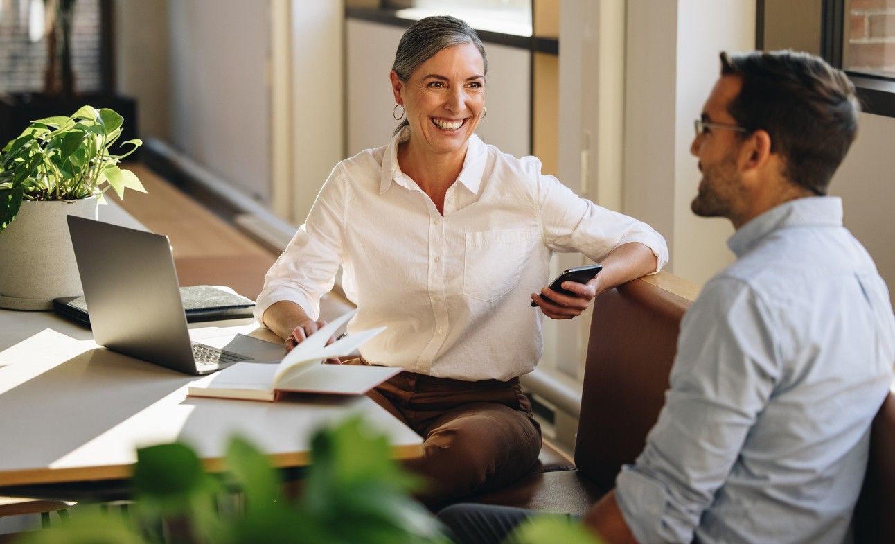 Dame og mann snakker sammen ved skrivebordet. bilde.