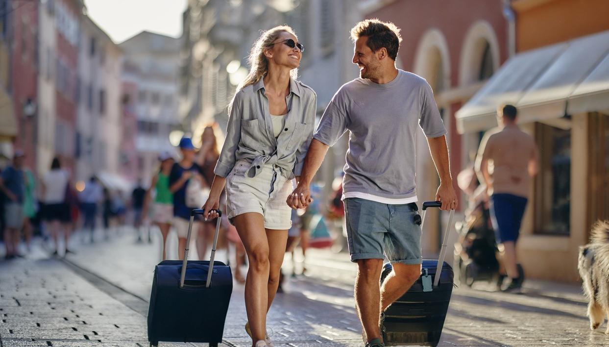 Par på ferietur går med kofferter gjennom byen. bilde.