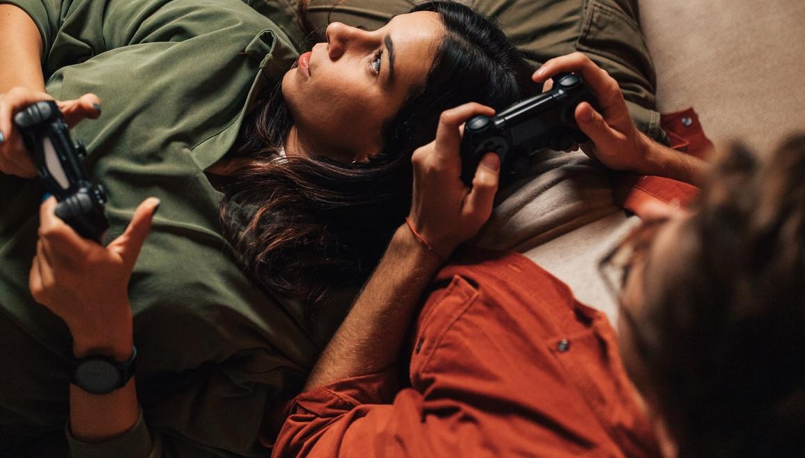 Ett par ligger i soffan och spelar tv-spel