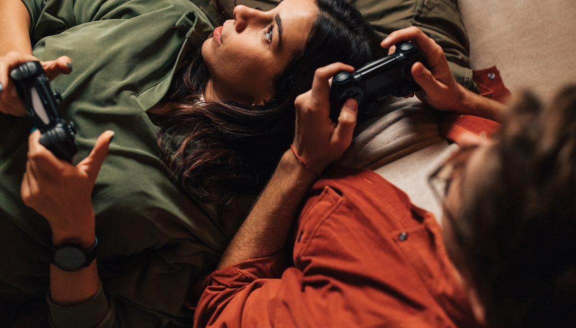 Ett par ligger i soffan och spelar tv-spel