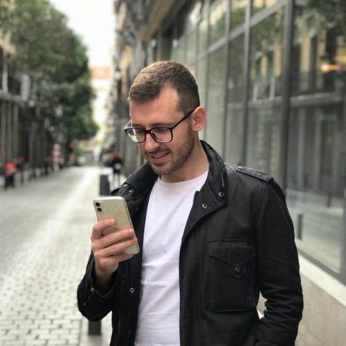 Mies katsoo puhelimensa näyttöä kadulla. Valokuva.