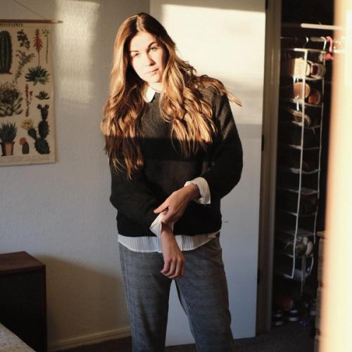 Nainen pukeutumassa kotonaan. Valokuva.