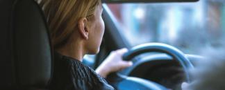 Dame kjører bil. Sett fra baksetet. bilde.