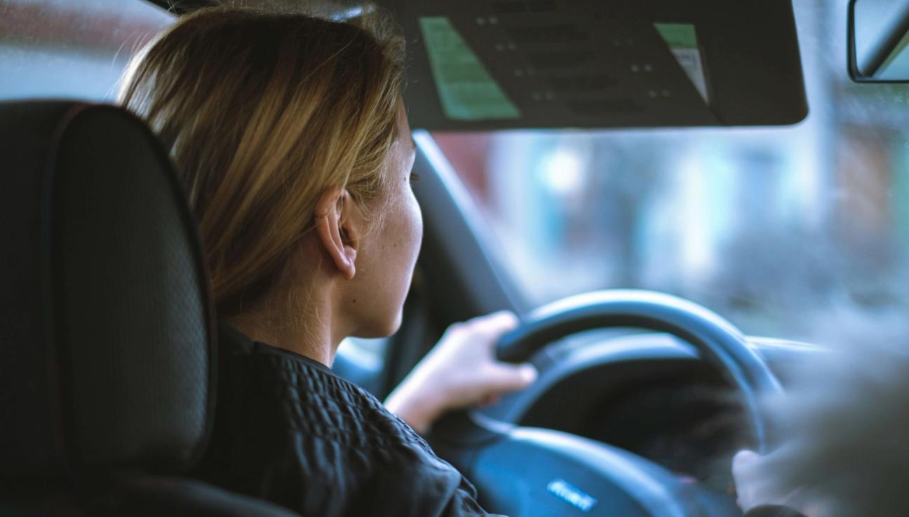 Dame kjører bil. Sett fra baksetet. bilde.