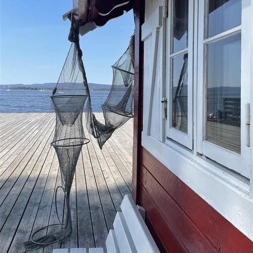 Sjøbod på brygge. Fiskenett henger på siden av sjøboden. bilde.