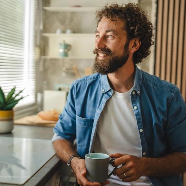 Mann med kaffekopp ser ut av vinduet. bilde.
