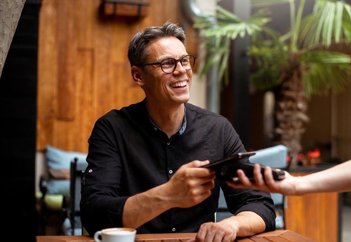A smiling man paying for a coffee with his mobile phone. picture.