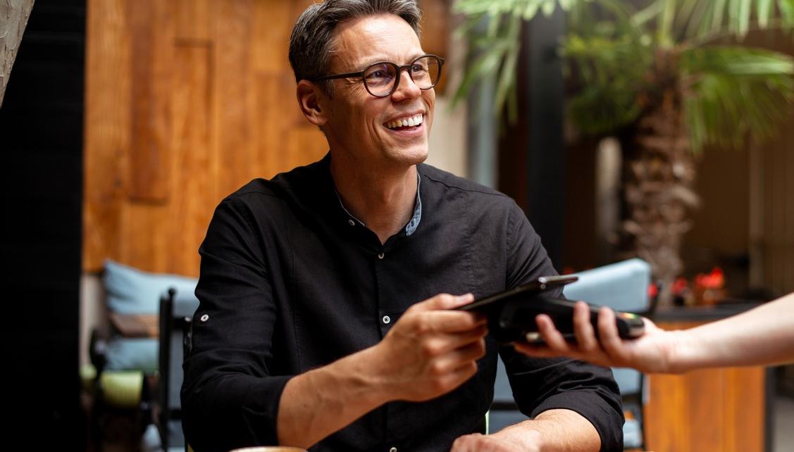 A smiling man paying for a coffee with his mobile phone. picture.