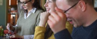 A group of friends is sitting around a table, eating and laughing.