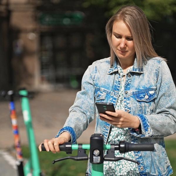 Kvinne betaler elsparkesykkel med Morrow Bank kredittkort i mobilen. bilde.