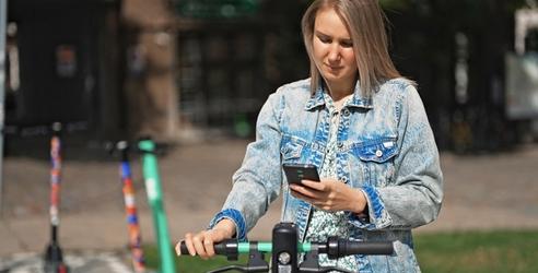 Kvinne betaler elsparkesykkel med Morrow Bank kredittkort i mobilen. bilde.