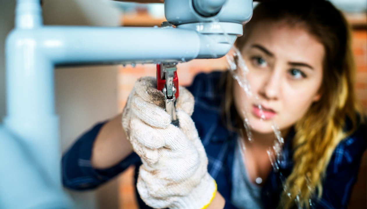 A faucet is leaking, and a handy woman is fixing it. picture